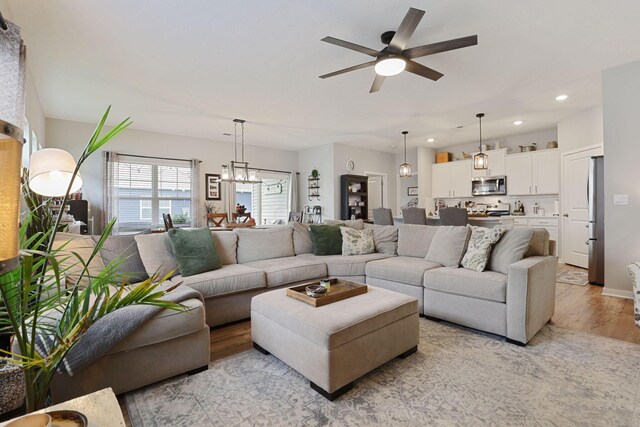 living room with light hardwood / wood-style flooring and ceiling fan with notable chandelier