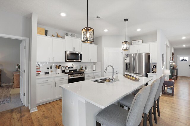 kitchen with white cabinets, appliances with stainless steel finishes, pendant lighting, and sink