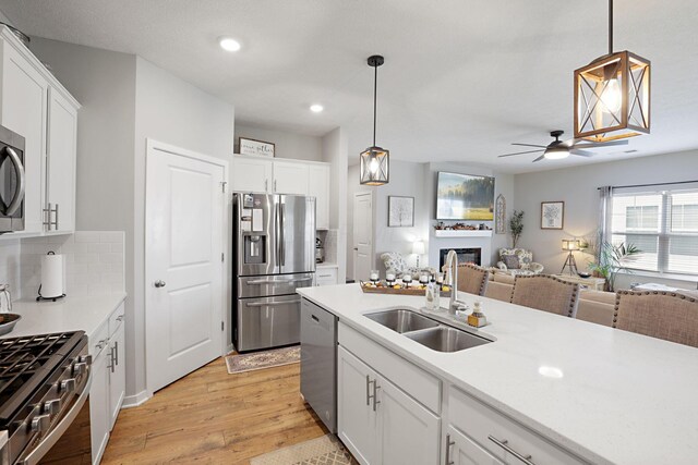 kitchen featuring white cabinetry, sink, hanging light fixtures, and appliances with stainless steel finishes