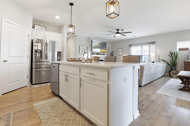 kitchen with pendant lighting, a center island, light hardwood / wood-style flooring, appliances with stainless steel finishes, and white cabinetry