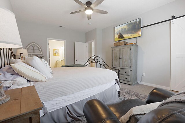 bedroom featuring carpet floors, a barn door, ensuite bathroom, and ceiling fan