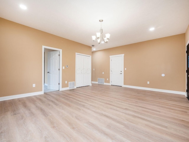 spare room with light hardwood / wood-style flooring and a notable chandelier