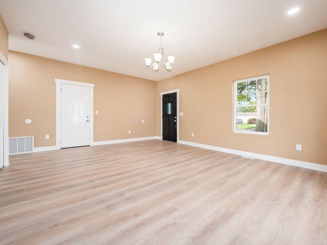 empty room featuring light hardwood / wood-style flooring and a chandelier