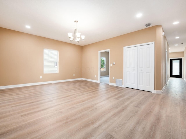 spare room with light wood-type flooring and an inviting chandelier