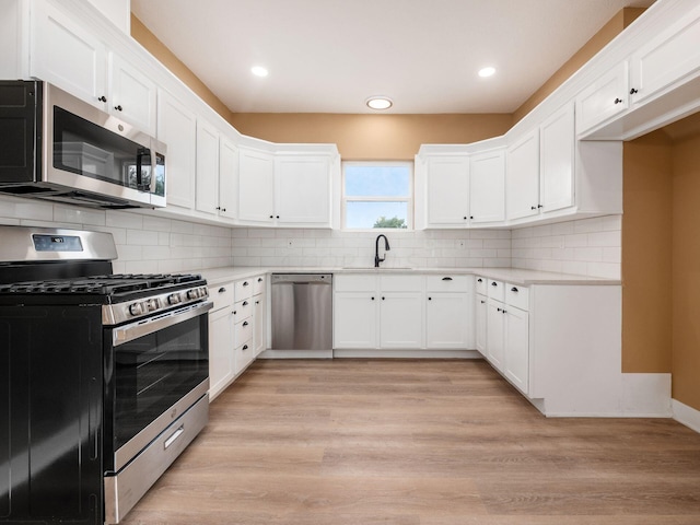 kitchen featuring stainless steel appliances, white cabinetry, and light hardwood / wood-style floors