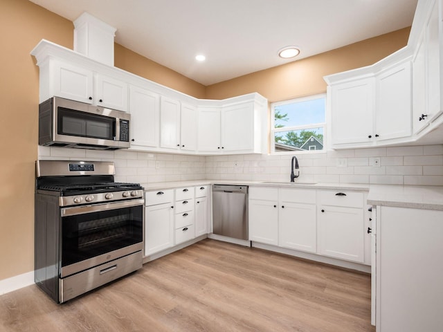 kitchen with sink, white cabinets, stainless steel appliances, and light hardwood / wood-style floors