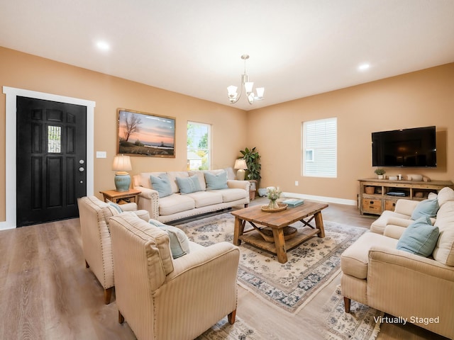 living room with light hardwood / wood-style floors, an inviting chandelier, and a healthy amount of sunlight