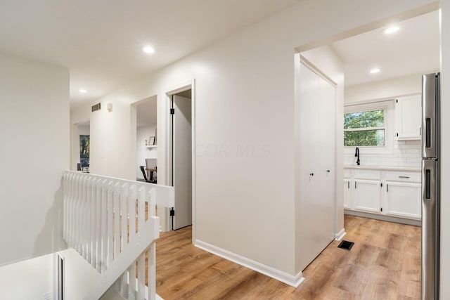 hallway featuring sink and light hardwood / wood-style flooring