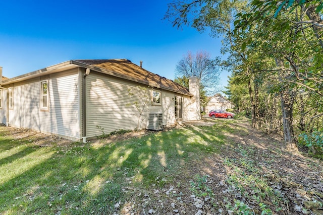 view of property exterior with central AC and a lawn