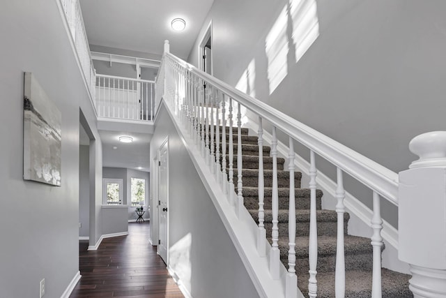 stairway with a towering ceiling and hardwood / wood-style flooring