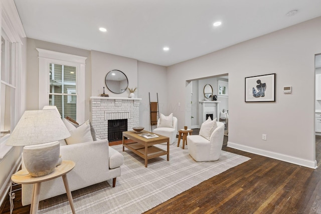 living room featuring wood-type flooring and a brick fireplace