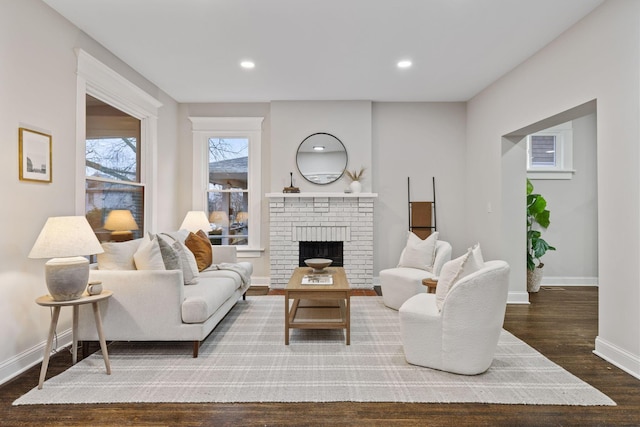 living room featuring dark wood-type flooring and a brick fireplace