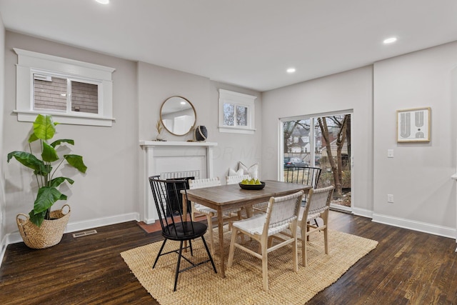 dining space featuring dark wood-type flooring and a fireplace