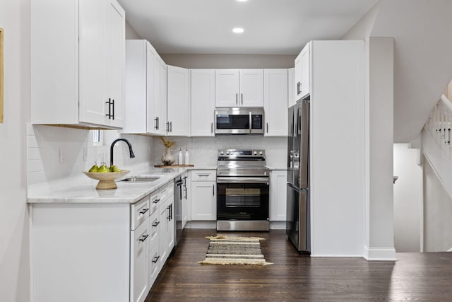 kitchen featuring stainless steel appliances, sink, white cabinets, and backsplash