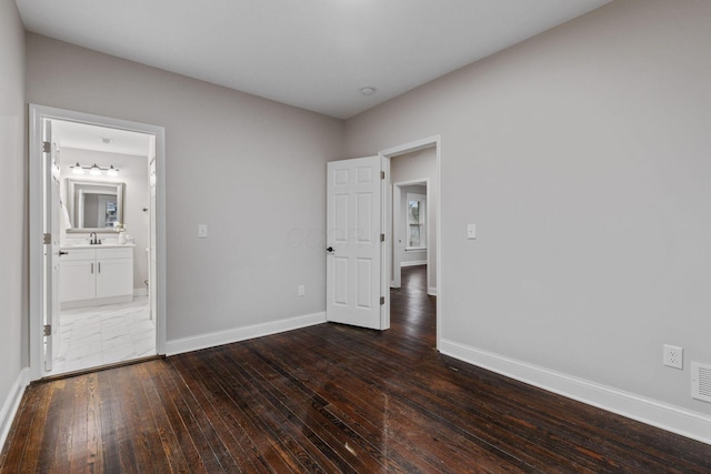 unfurnished bedroom featuring dark wood-type flooring and ensuite bathroom