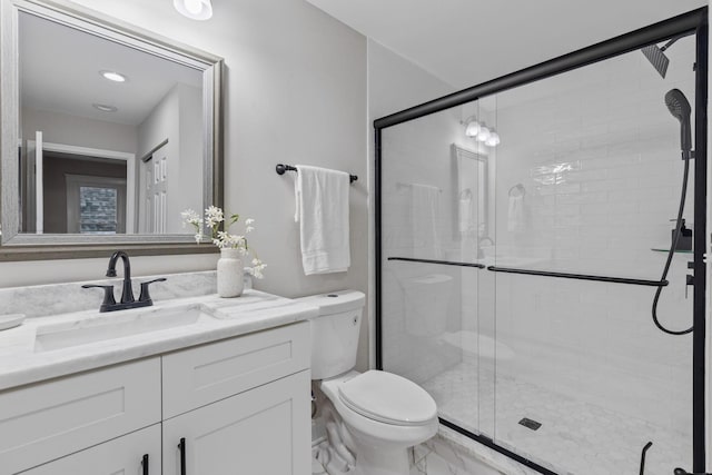 bathroom featuring vanity, a shower with shower door, and toilet