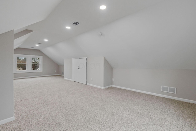 additional living space featuring lofted ceiling and light carpet