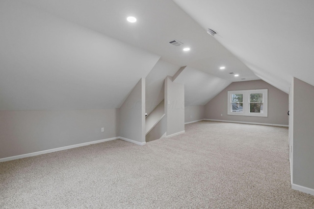 additional living space featuring light carpet and vaulted ceiling