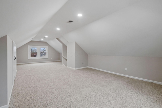 additional living space featuring light colored carpet and lofted ceiling