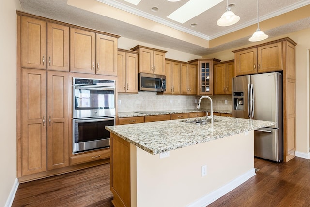 kitchen featuring a skylight, light stone countertops, sink, decorative backsplash, and appliances with stainless steel finishes