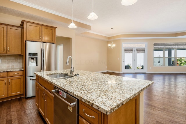 kitchen featuring stainless steel appliances, a kitchen island with sink, crown molding, sink, and hanging light fixtures