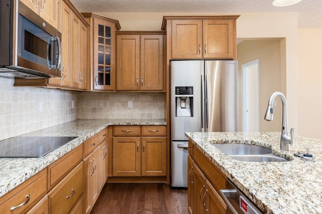 kitchen with backsplash, dark wood-type flooring, sink, light stone countertops, and appliances with stainless steel finishes