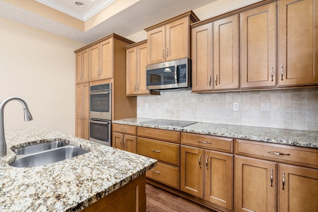 kitchen with light stone countertops, tasteful backsplash, stainless steel appliances, crown molding, and sink