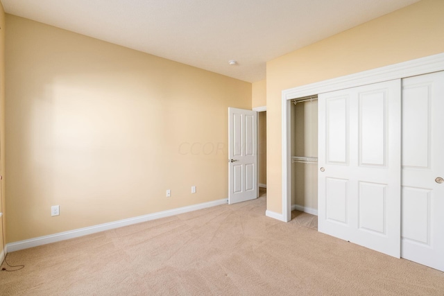 unfurnished bedroom featuring light colored carpet and a closet