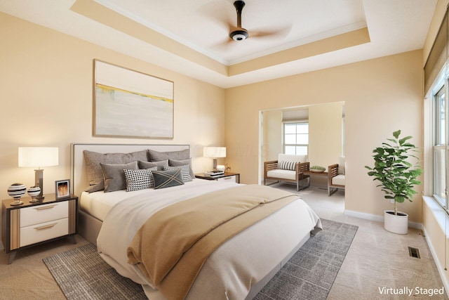 bedroom with ceiling fan, light colored carpet, ornamental molding, and a tray ceiling