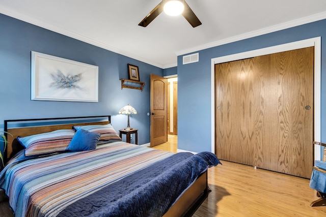 bedroom featuring ceiling fan, a closet, crown molding, and light hardwood / wood-style flooring