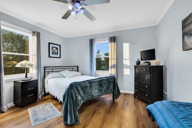 bedroom featuring hardwood / wood-style floors, ceiling fan, ornamental molding, and multiple windows