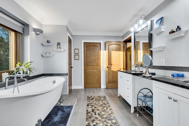 bathroom with vanity, ornamental molding, and a tub to relax in