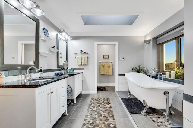 bathroom featuring a skylight, a bathtub, vanity, and ornamental molding