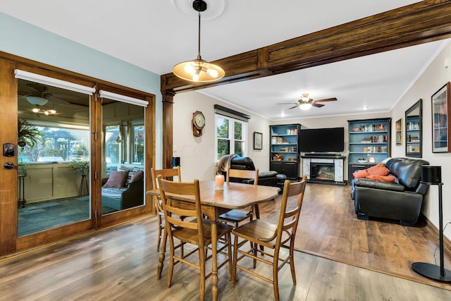 dining space with ceiling fan, crown molding, built in features, and hardwood / wood-style flooring