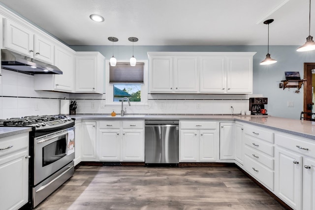 kitchen with white cabinets, appliances with stainless steel finishes, and decorative light fixtures