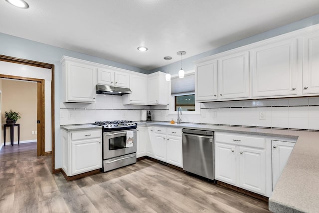 kitchen featuring white cabinets, hardwood / wood-style floors, stainless steel appliances, and hanging light fixtures