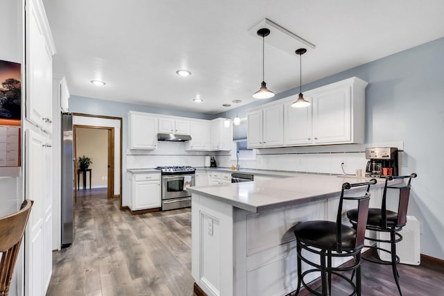 kitchen featuring a kitchen breakfast bar, light hardwood / wood-style flooring, white cabinetry, kitchen peninsula, and stainless steel appliances