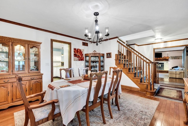 dining area with crown molding, light hardwood / wood-style flooring, and a notable chandelier