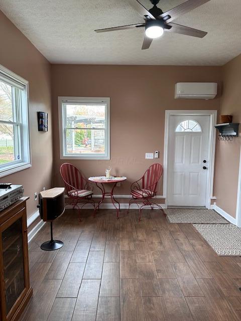 entrance foyer featuring a healthy amount of sunlight, wood-type flooring, a textured ceiling, and a wall mounted AC