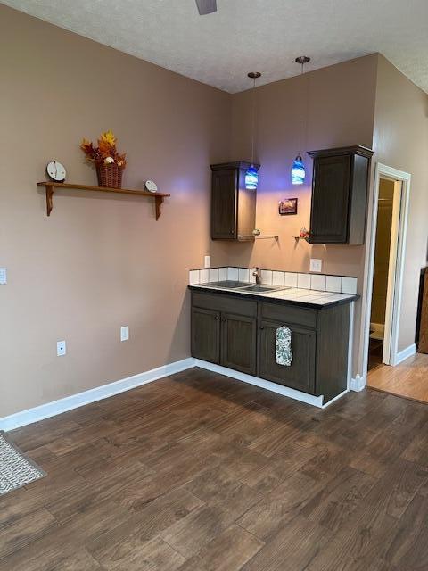 kitchen featuring dark brown cabinetry, dark hardwood / wood-style flooring, pendant lighting, and a textured ceiling