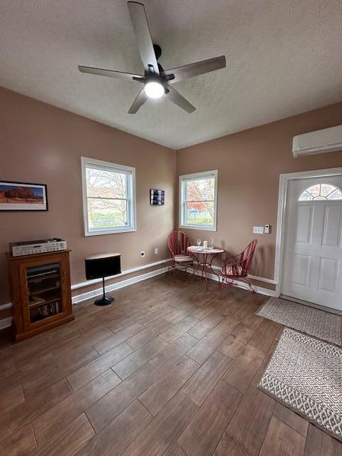 entrance foyer with a textured ceiling, hardwood / wood-style flooring, a wall mounted AC, and ceiling fan