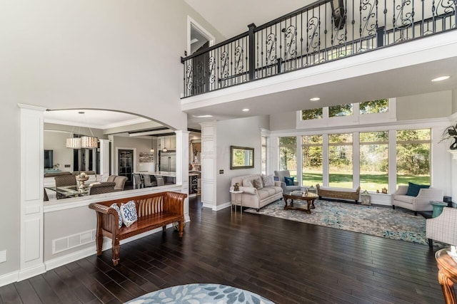 living room with ornate columns, wood-type flooring, and a high ceiling