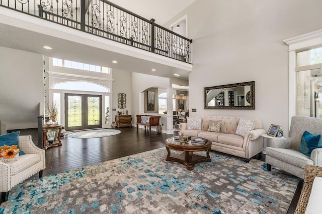 living room featuring a chandelier, wood-type flooring, french doors, and a high ceiling