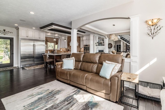 living room with a textured ceiling, dark hardwood / wood-style flooring, ornamental molding, and sink