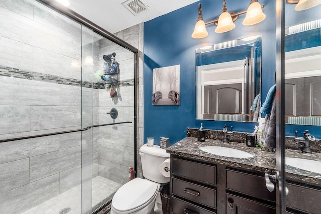 bathroom with a shower with door, vanity, and toilet