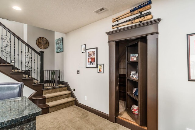 stairs featuring a textured ceiling and carpet floors