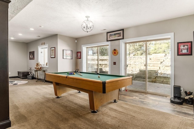 rec room featuring a textured ceiling, hardwood / wood-style flooring, an inviting chandelier, and billiards