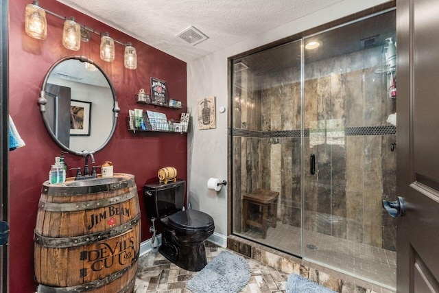 bathroom with vanity, a shower with shower door, a textured ceiling, and toilet