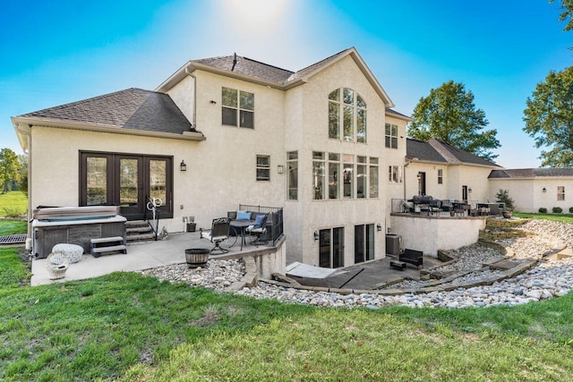 rear view of house with french doors, a patio, a hot tub, and a lawn