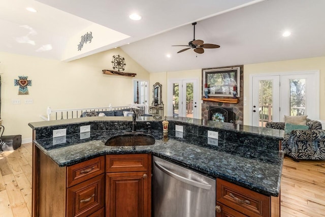 kitchen featuring stainless steel dishwasher, vaulted ceiling, sink, light hardwood / wood-style floors, and plenty of natural light